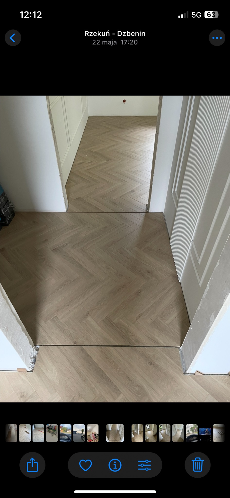 Jasny parkiet ułożony w jodełkę, widoczny z perspektywy progu drzwi. Białe, klasyczne drzwi po prawej stronie kadru. Widok na kolejne pomieszczenie.