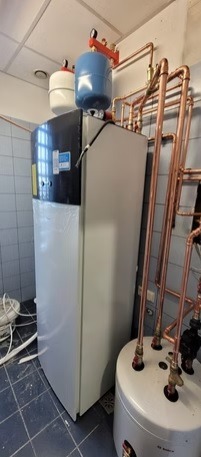 Pompa ciepła z zbiornikiem buforowym i miedzianą instalacją w kotłowni. Montaż w Poznaniu. Widoczne elementy instalacji i podłączenia.