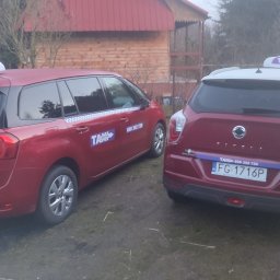 Jarosław Sobczak - Sobkon - Dwa czerwone samochody taxi różnych marek, Citroen i SsangYong, stojące obok siebie na zewnątrz, z widocznymi oznaczeniami taxi i numerami telefonów.