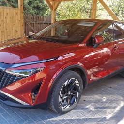 Jarosław Sobczak - Sobkon - Czerwony Opel Grandland z widoczną tablicą rejestracyjną, zaparkowany na brukowanej nawierzchni pod drewnianą konstrukcją. Auto w czystym, zadbanym stanie.