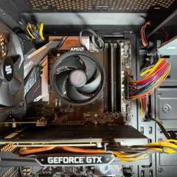 Patryk Kaszubski - Wnętrze komputera stacjonarnego z widoczną kartą graficzną GeForce GTX, procesorem AMD z chłodzeniem i kolorowymi kablami zasilającymi. Widok z góry.
