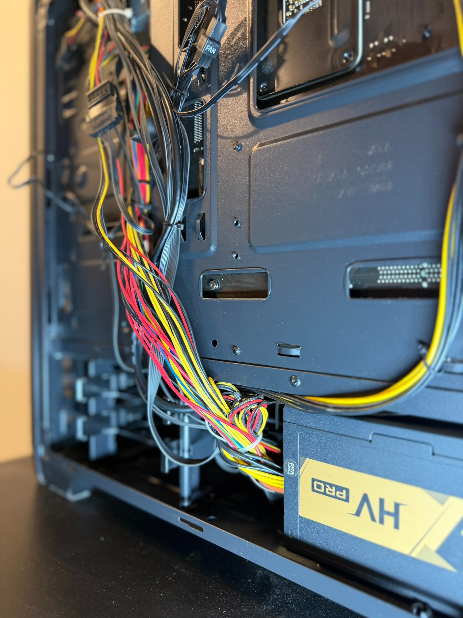 Wnętrze obudowy komputera stacjonarnego z widocznym zasilaczem HV Pro i uporządkowanymi kablami w kolorach: czarnym, żółtym, czerwonym i niebieskim.