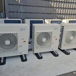 Mateusz Struzik MSAIR - Rząd jednostek zewnętrznych klimatyzacji Daikin SkyAir na dachu, z widocznymi detalami montażu i szarą dachówką w tle. Widok z boku, lekko z góry.