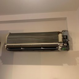 Mateusz Struzik MSAIR - Ścienna jednostka klimatyzacji po zdjęciu obudowy, widoczne elementy wewnętrzne i podłączenia elektryczne. Urządzenie zamontowane na jasnej ścianie.