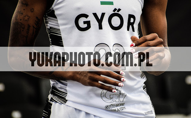 Zbliżenie na koszulkę sportową z napisem 'GYÖR' i numerem 22, dłonie z manicure z motywem sportowym. Widoczne tatuaże na ramieniu. Detal stroju sportowego.