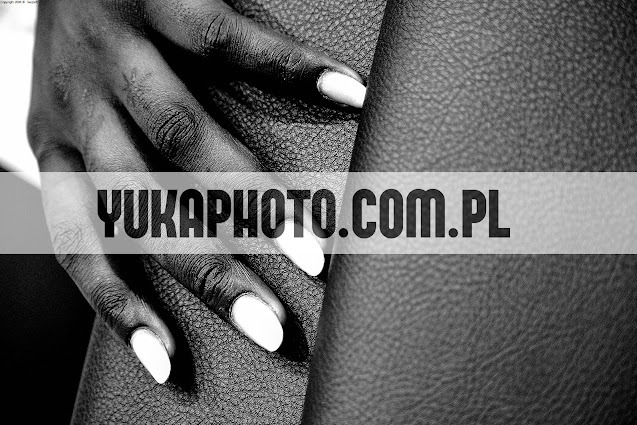 Czarno-białe zbliżenie dłoni o ciemnej karnacji z białym manicure na tle skóry. Widoczny znak wodny YUKAPHOTO.COM.PL.