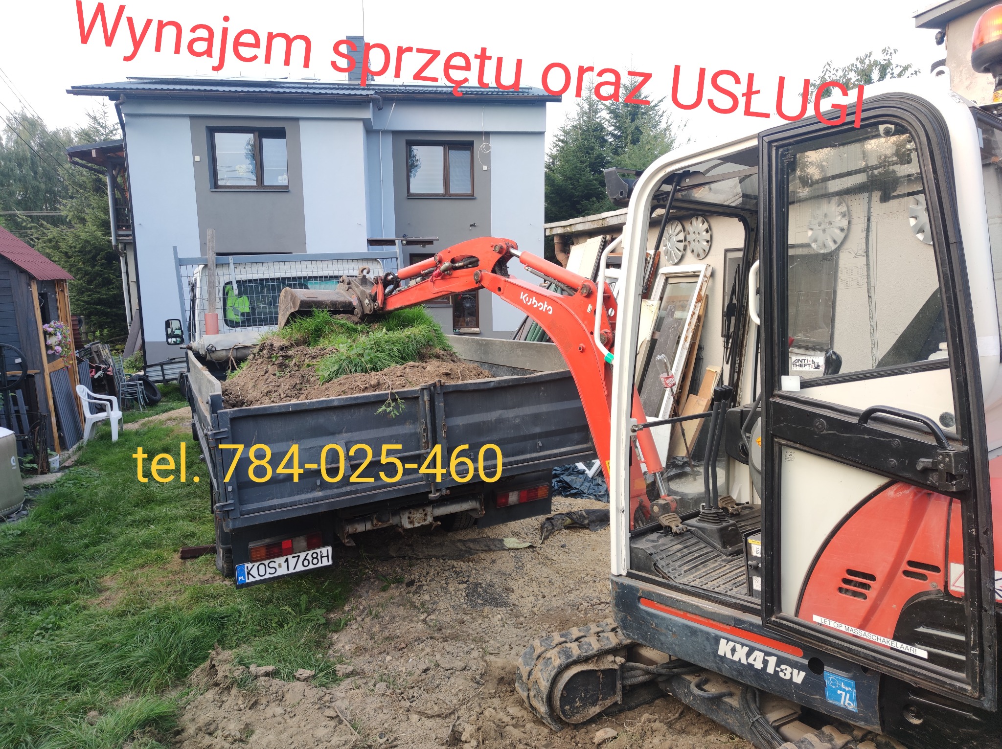 Mini koparka Kubota nabiera ziemię do skrzyni ładunkowej ciężarówki na tle domu. Widoczny numer telefonu kontaktowego.