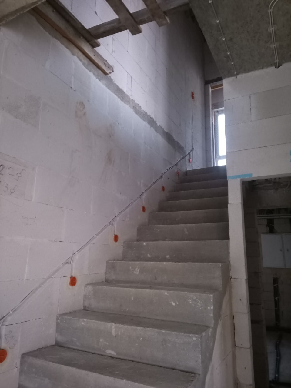 Surowy beton schodów z instalacją elektryczną w trakcie montażu, widoczne puszki. Prace w budynku w Wysokiem Mazowieckiem.