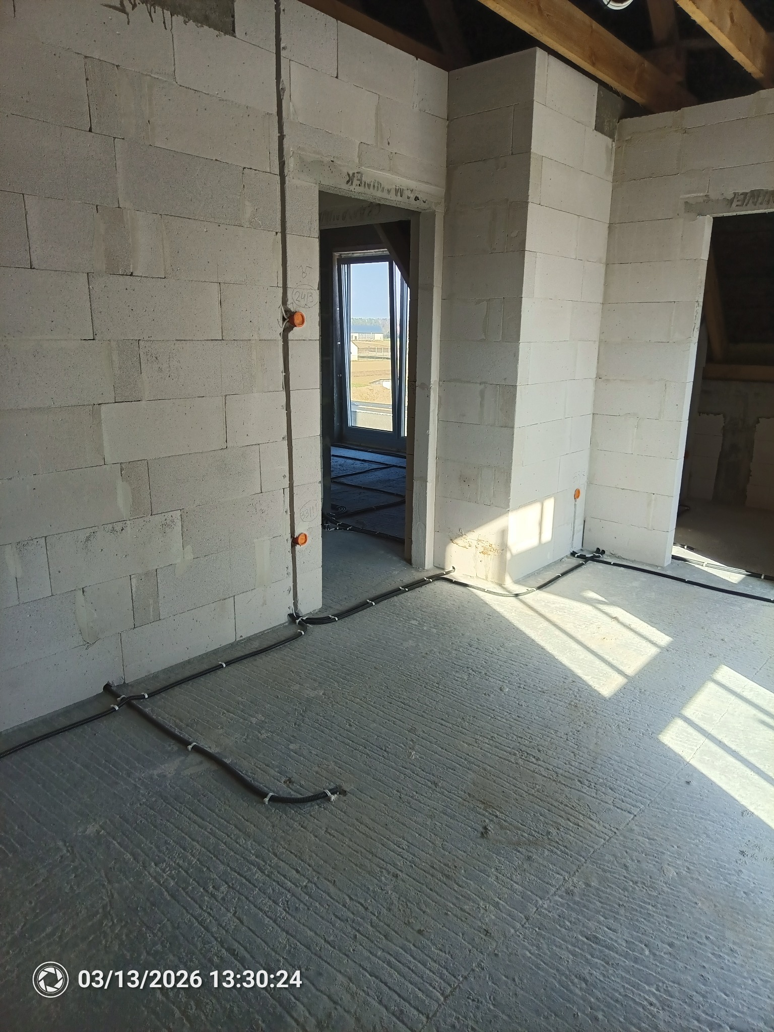 Surowy stan: przewody elektryczne ułożone na podłodze i wyprowadzone na ścianach z pustaków w nowym budynku. Widoczne puszki instalacyjne.