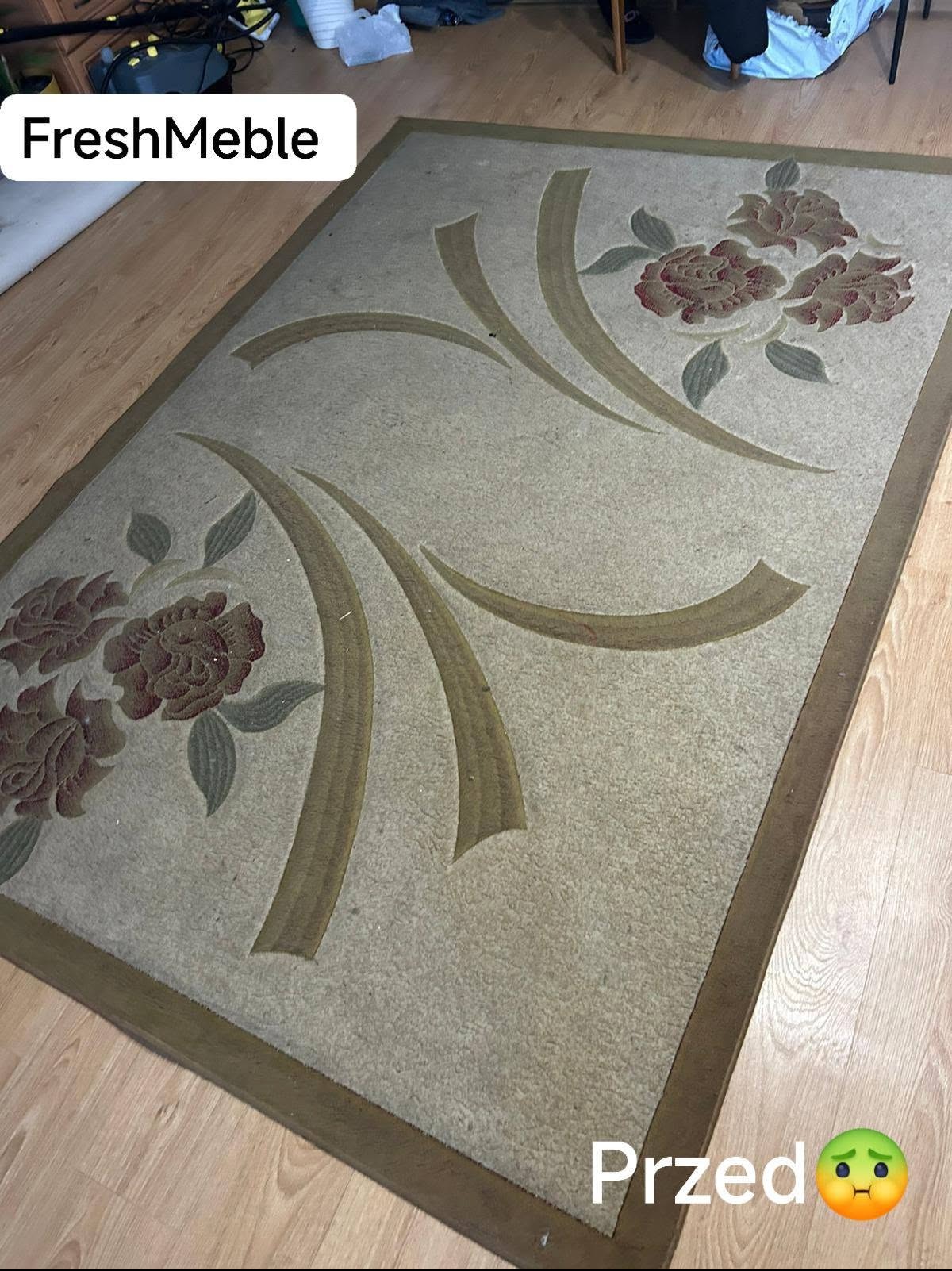Beżowy dywan z motywem kwiatowym przed czyszczeniem, widoczne zabrudzenia. Ujęcie z góry, perspektywa z narożnika dywanu. Na podłodze widoczne panele.