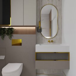 Lofera - Nowoczesna łazienka z owalnym lustrem w złotej ramie, wiszącą szafką z umywalką i toaletą. Dekoracyjne panele ścienne, akcenty złota i roślinny detal dodają elegancji.