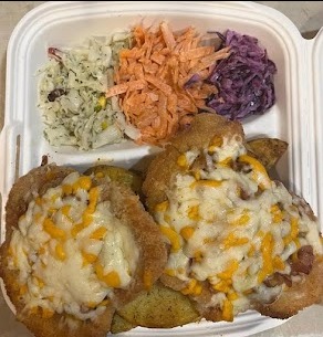 Danie cateringowe w białym pojemniku: sznycel z serem i boczkiem na ziemniakach, obok trzy rodzaje surówek - z kapusty białej, marchewki i kapusty czerwonej.