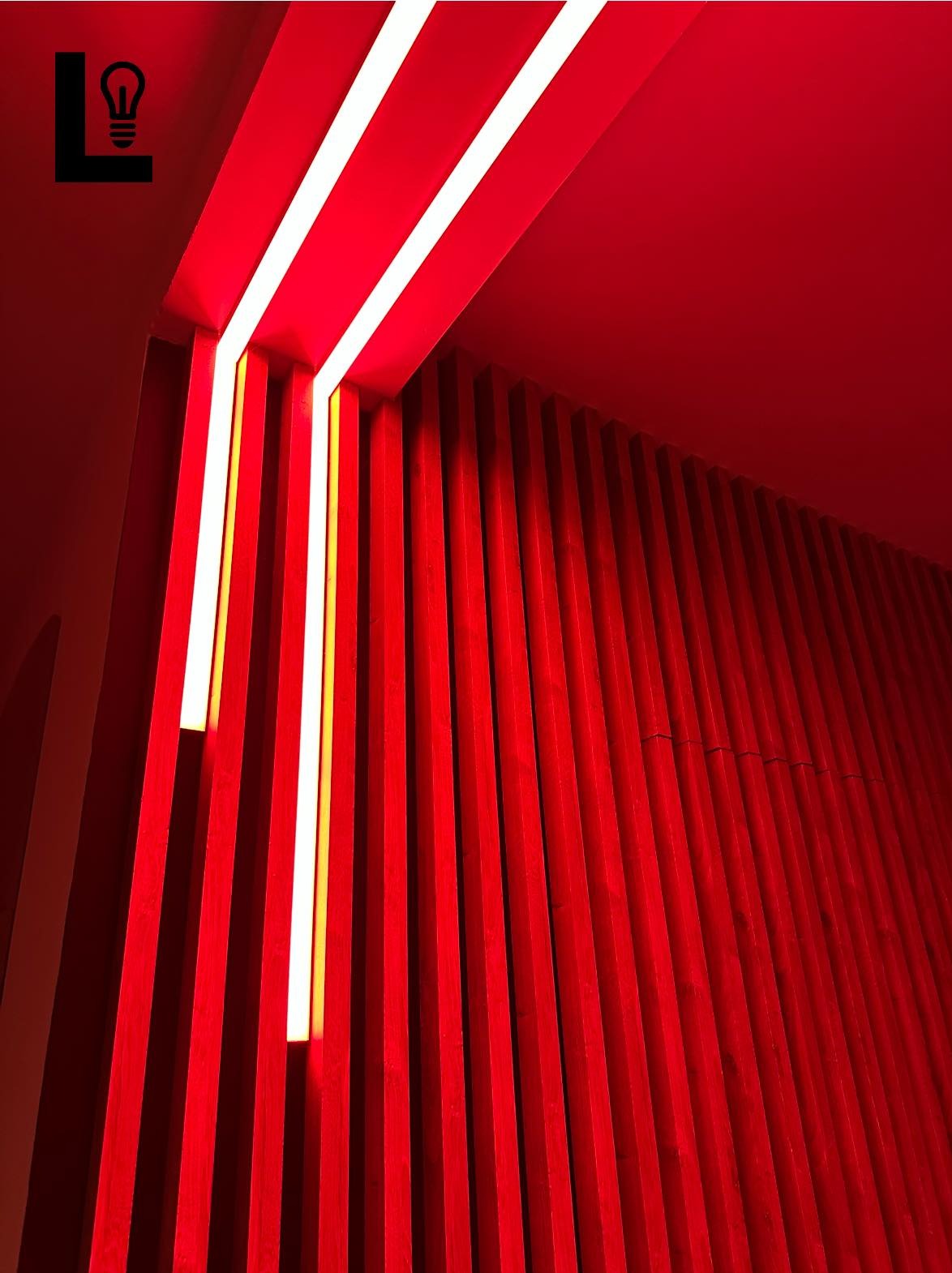Czerwone, pionowe panele ścienne z wbudowanym, białym oświetleniem LED, tworzące nowoczesny efekt wizualny. Nietypowe ujęcie z dołu.
