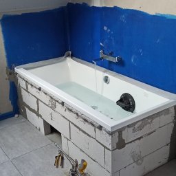 Oleg Andronik AndroBud - Wanna obudowana bloczkami, ściany zabezpieczone folią w płynie. Widoczne narzędzia i fragment instalacji. Etap prac wykończeniowych w łazience.