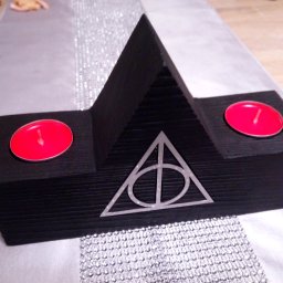 JJ STEP Janusz Jaroński - Czarny, drewniany świecznik w kształcie symbolu Insygniów Śmierci z czerwonymi świeczkami na srebrnym bieżniku.