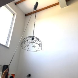 ALLCLEAN Usługi Sprzątające JOACHIM SCHÄFER - Wysoki sufit i nowoczesna lampa czyszczone z kurzu za pomocą teleskopowej miotełki. Widoczne drewniane belki stropowe i minimalistyczny wystrój wnętrza.