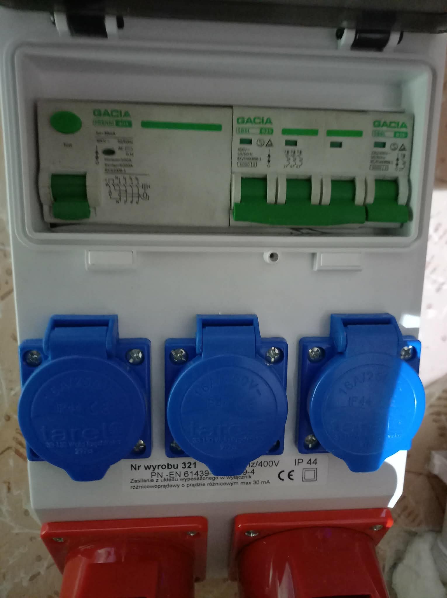 Rozdzielnica elektryczna z wyłącznikami różnicowoprądowymi i gniazdami siłowymi (16A/400V) w obudowie. Widoczne oznaczenia producenta i parametry techniczne.