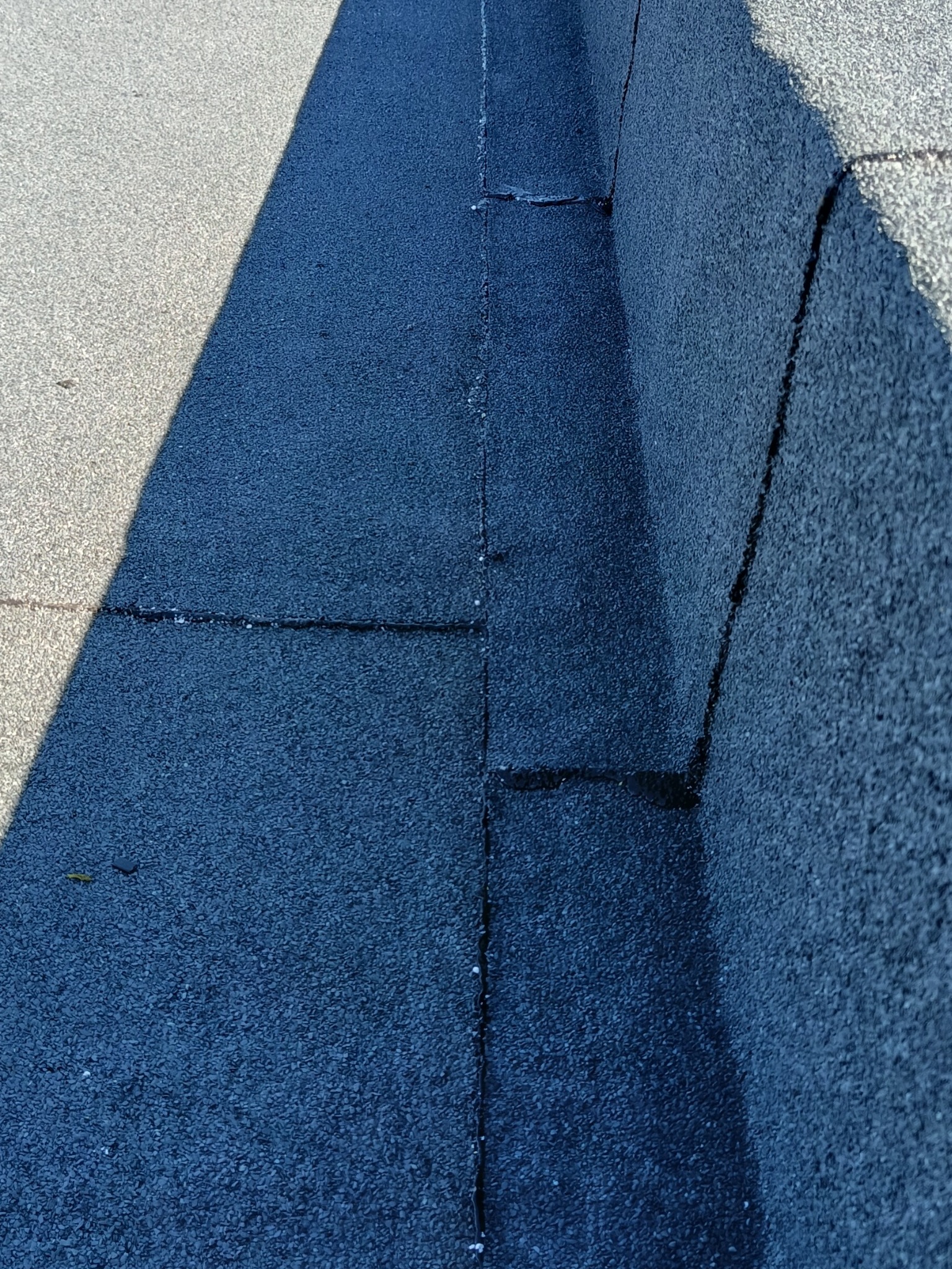 Szczegółowe ujęcie dachu pokrytego papą, z widocznymi łączeniami i fakturą materiału. Cień podkreśla strukturę powierzchni. Widoczne drobne uszkodzenia.