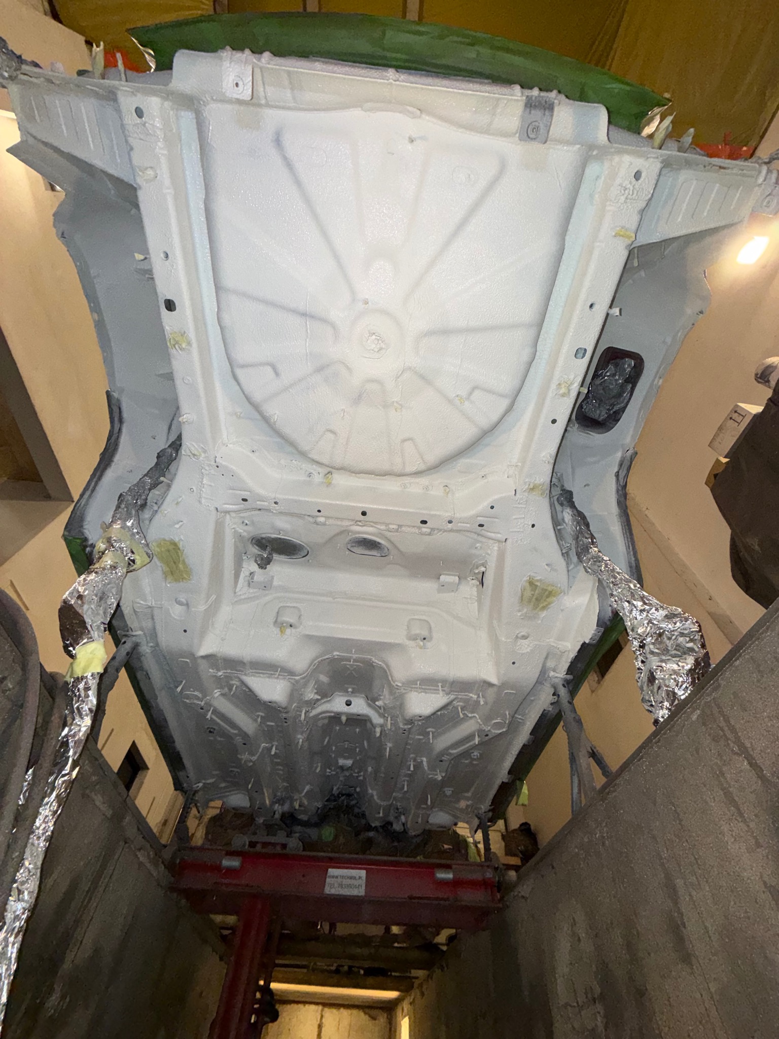 Podwozie samochodu po piaskowaniu i zabezpieczeniu antykorozyjnym, widoczne detale konstrukcyjne i zabezpieczone elementy. Auto na podnośniku w warsztacie.