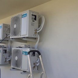 Martin Serwis - Cztery klimatyzatory Hisense zamontowane na zewnątrz budynku, połączone rurami. Widoczna drabina i narzędzia, sugerujące trwający montaż lub serwis.