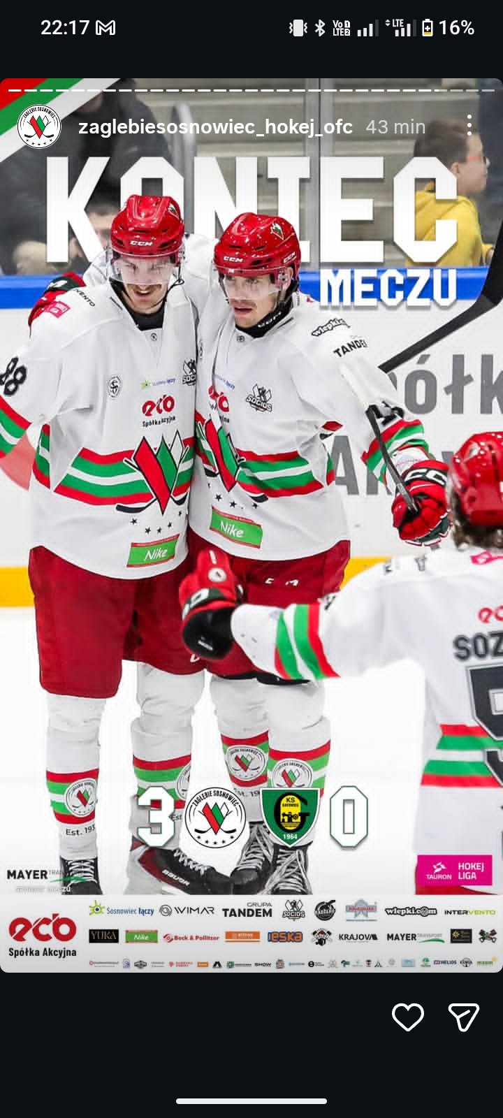 Dwóch hokeistów Zagłębia Sosnowiec w czerwonych kaskach i białych strojach z logotypami sponsorów, świętujących zwycięstwo 3:0 na tle trybun.