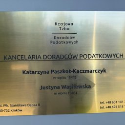 TaxOwl spółka z ograniczoną odpowiedzialnością - Złota, szczotkowana tabliczka informacyjna kancelarii doradców podatkowych w Krakowie, z nazwiskami Katarzyna Paszkot-Kaczmarczyk i Justyna Wasilewska, adresem i numerami telefonów.