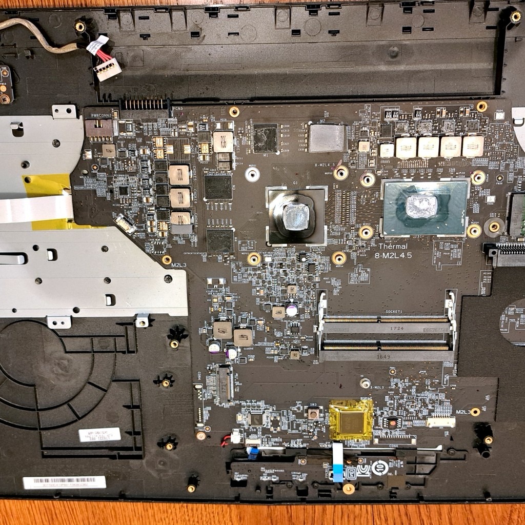 Wnętrze laptopa z widoczną płytą główną, elementami chłodzenia i złączami. Detaliczna prezentacja elektroniki w trakcie naprawy lub modernizacji.