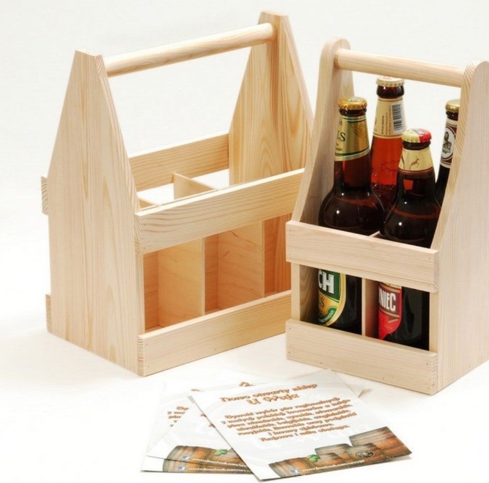 Dwa drewniane nosidła na piwo, jedno puste, drugie z butelkami, oraz ulotki reklamowe z logo sklepu na białym tle. Jasne drewno, naturalne światło.