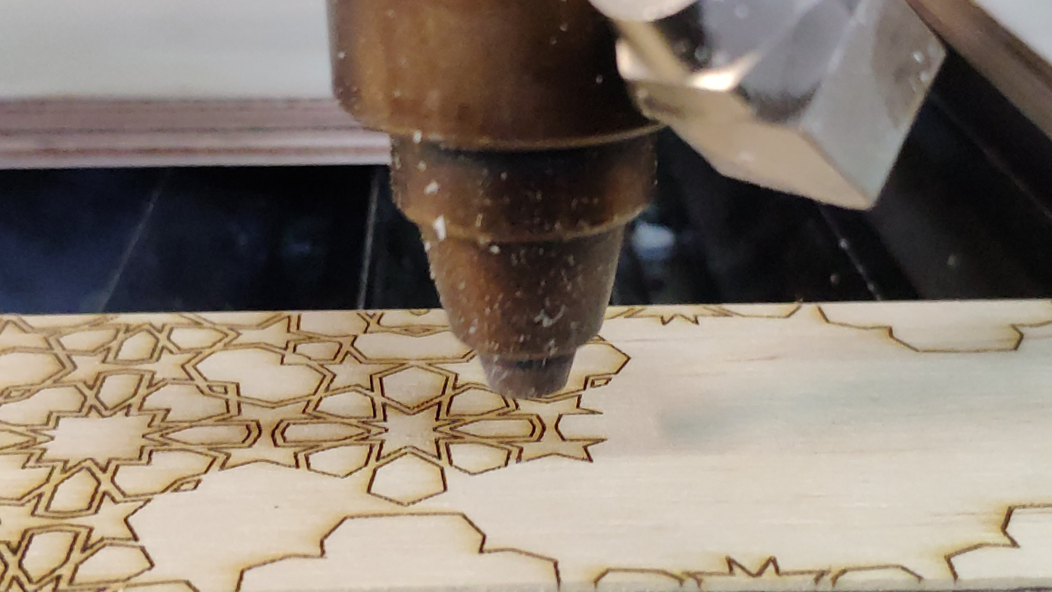 Precyzyjna obróbka CNC drewna: frezarka wycina skomplikowany, geometryczny wzór na jasnym drewnie. Detal w trakcie pracy, bliski kadr.