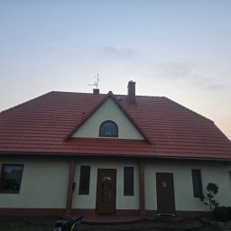 Czas na Mycie - Dom jednorodzinny z czerwonym dachem, widoczny z poziomu gruntu, z elementami wykończenia w kolorze brązowym. Na dachu antena i komin.