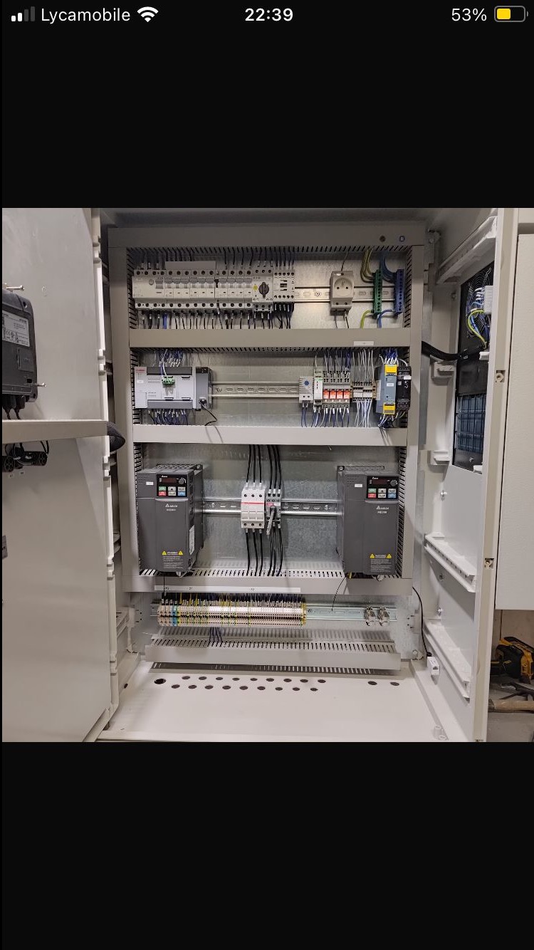 Otwarta szafa sterownicza z precyzyjnie ułożonymi przewodami, zabezpieczeniami i modułami sterującymi. Widoczne dwa falowniki Delta. Całość w jasnej, metalowej obudowie.