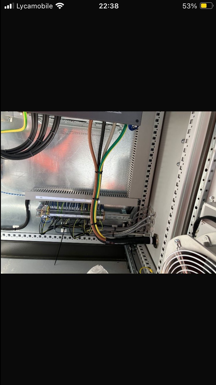 Wnętrze szafy sterowniczej z podłączonymi przewodami. Widoczne listwy zaciskowe, kable w różnych kolorach oraz elementy montażowe. Ujęcie z bliska, detale instalacji.