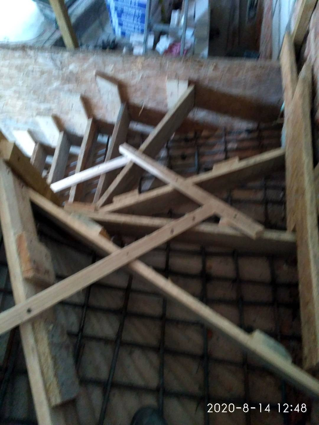 Konstrukcja drewniana schodów w trakcie budowy, widoczne zbrojenie w podłodze, surowy stan, data i godzina na zdjęciu.