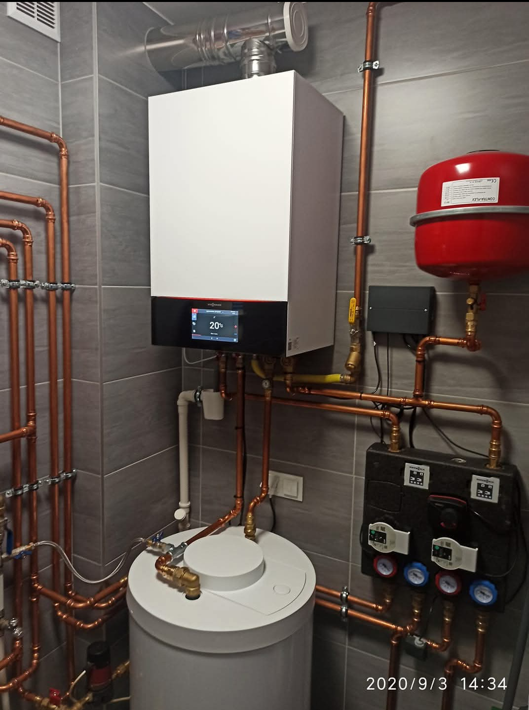 Nowoczesny piec gazowy Viessmann z instalacją CO w kotłowni, widok z dołu. Realizacja w Luzino. Miedziane rury i szara glazura.