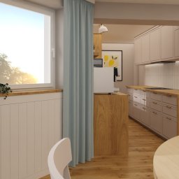 Flow Studio Projektowe Ewa Zarazińska - Jasna kuchnia z drewnianym blatem i pastelowymi szafkami, widok z jadalni z błękitną zasłoną i rośliną w oknie. Minimalistyczny design z akcentami naturalnego drewna.
