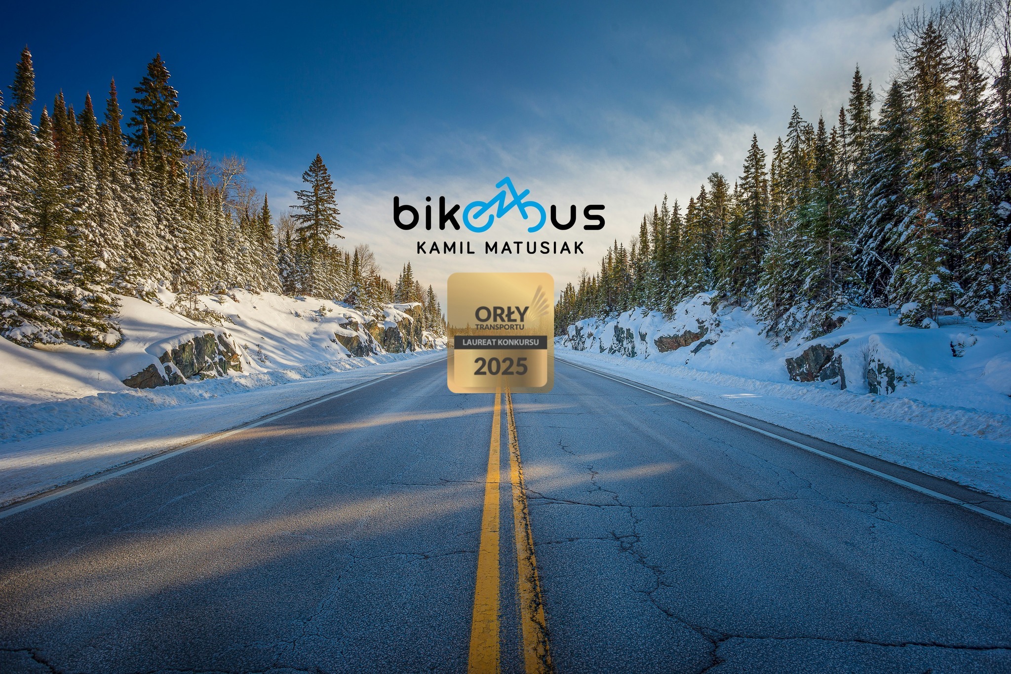 Zimowy krajobraz z drogą, logo 'bikeBUS Kamil Matusiak' i nagrodą 'Orły Transportu 2025'. Perspektywa centralna, błękitne niebo, ośnieżone drzewa. Promocja firmy transportowej.