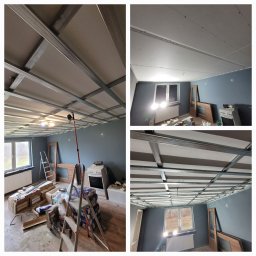 Majstry.pl Tadeusz Gera, Rafał Zych spółka cywilna - Montaż sufitu podwieszanego z płyt gipsowo-kartonowych na metalowej konstrukcji w remontowanym pokoju z szarymi ścianami i oknem. Widoczne materiały i drabina.