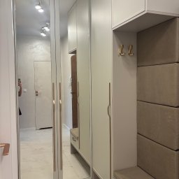 17 Studio Projektowe Sylwia Bierwiaczonek - Jasna szafa wnękowa z lustrami i siedziskiem w przedpokoju. Minimalistyczny design, złote akcenty, odbicie wnętrza mieszkania. Nowoczesne wykończenie.