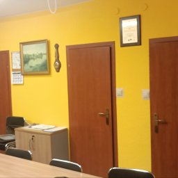 Patryk Buczkowski - Żółta ściana po odświeżeniu w biurze w Gdyni. Widoczne drzwi, obraz, szafki i stół konferencyjny. Ściana pomalowana na jednolity, intensywny kolor.