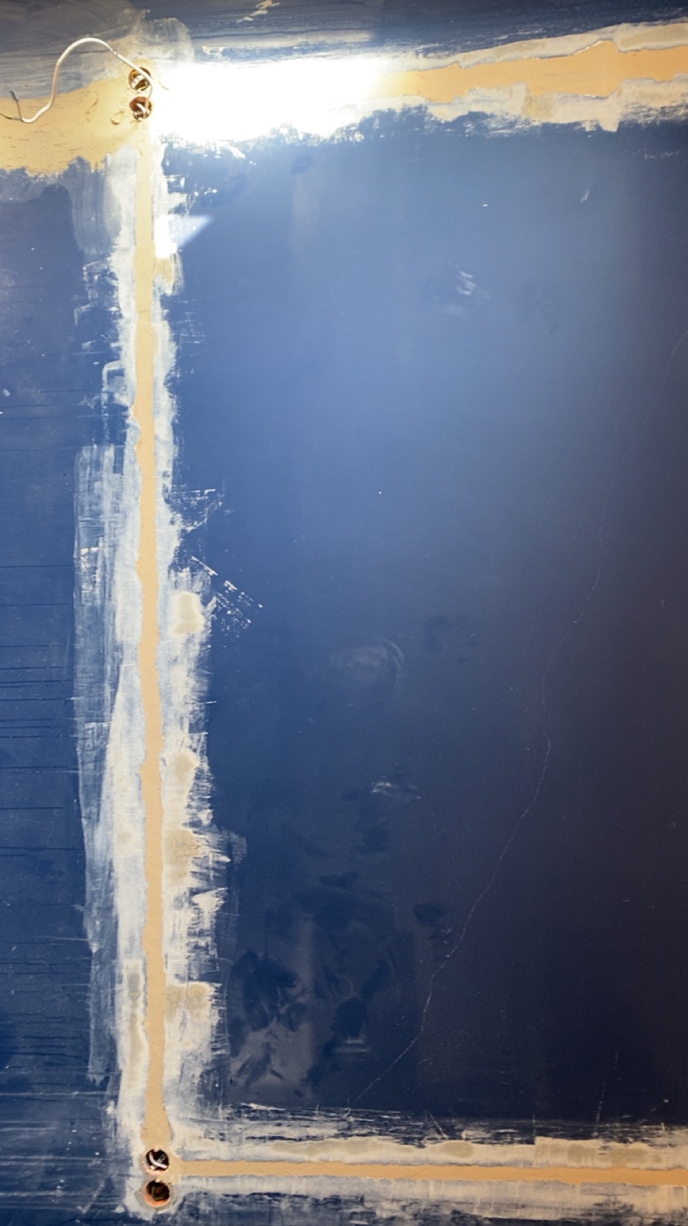 Przygotowanie ściany pod montaż oświetlenia: wyfrezowane bruzdy pod kable, częściowo zaszpachlowane, widoczne otwory na puszki elektryczne, niebieska ściana.