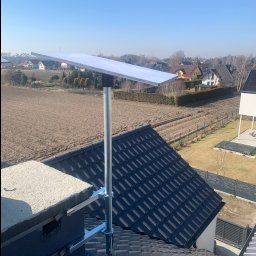 Yehor Chebotar - Antena satelitarna zamontowana na kominie domu jednorodzinnego z widokiem na okolicę w słoneczny dzień. Widoczne kable antenowe.