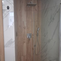 Kam-Bud - Nowoczesna kabina prysznicowa z drewnopodobnymi i marmurowymi płytkami, deszczownicą i szklaną ścianką. Minimalistyczny design, eleganckie wykończenie.