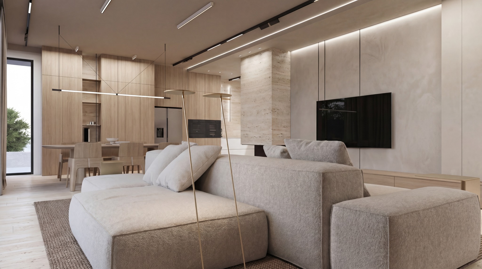 Jasne, przestronne wnętrze salonu z beżową sofą modułową, drewnianą zabudową i minimalistycznym oświetleniem. Widoczny stół z krzesłami i telewizor na ścianie.