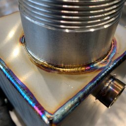 Metal Idustry Company Sp z O.O. - Precyzyjne spawy TIG na metalowej konstrukcji, widoczne tęczowe przebarwienia termiczne. Detal złącza cylindrycznego i krawędzi, wysoka jakość wykonania.