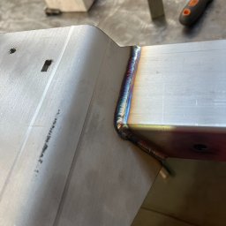 Metal Idustry Company Sp z O.O. - Precyzyjne spawanie narożnika metalowej konstrukcji. Widoczne ślady termiczne na spoinie, świadczące o wysokiej jakości wykonania. Detal z bliska, narzędzia w tle.