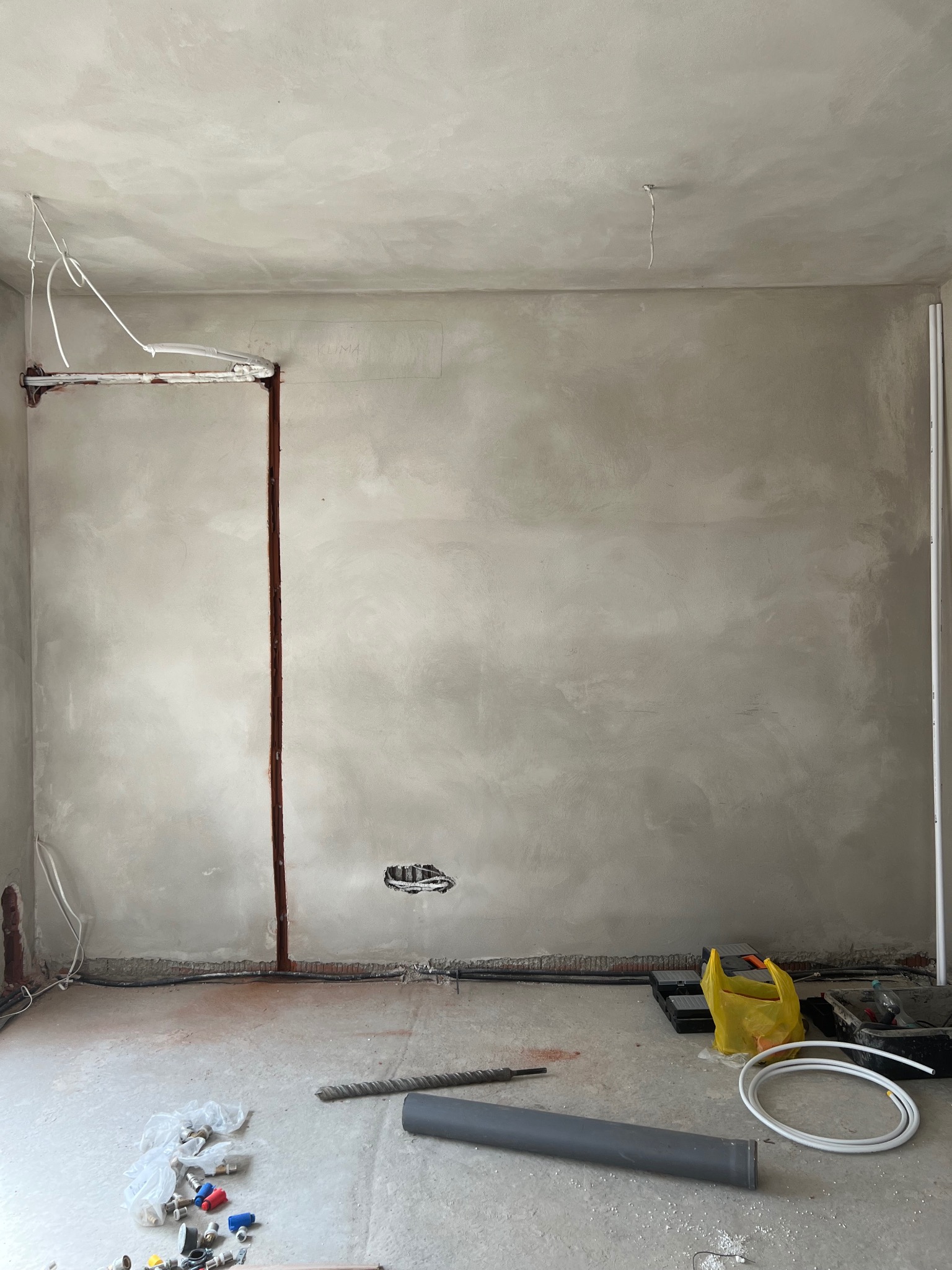 Wnętrze w trakcie montażu klimatyzacji: bruzdy w ścianie, rury, kable, narzędzia. Widoczne przygotowania do instalacji systemu klimatyzacyjnego w pomieszczeniu.