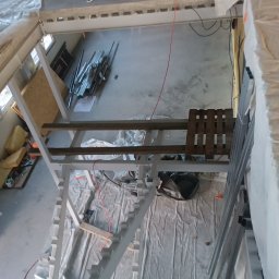 CBL Technic - Wnętrze w budowie: metalowa konstrukcja schodów dwubiegowych przygotowana pod wylanie stopni betonowych. Widok z góry na surowy stan prac.