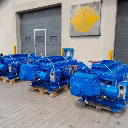 CBL Technic - Trzy niebieskie, identyczne maszyny przemysłowe na paletach, ustawione przed szarą halą z bramami. Widoczny znak firmowy na budynku. Maszyny zabezpieczone białym sznurkiem.