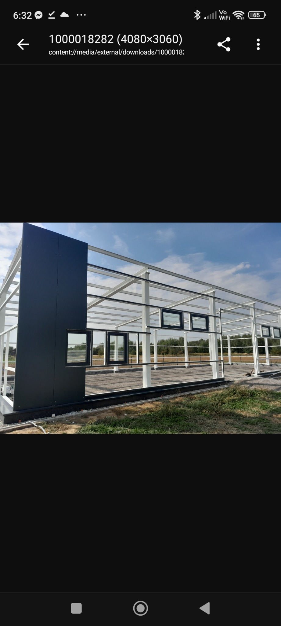 Konstrukcja stalowa hali w Bochni, z widocznymi oknami i elementami obudowy. Biała rama konstrukcji na tle błękitnego nieba. Etap budowy.