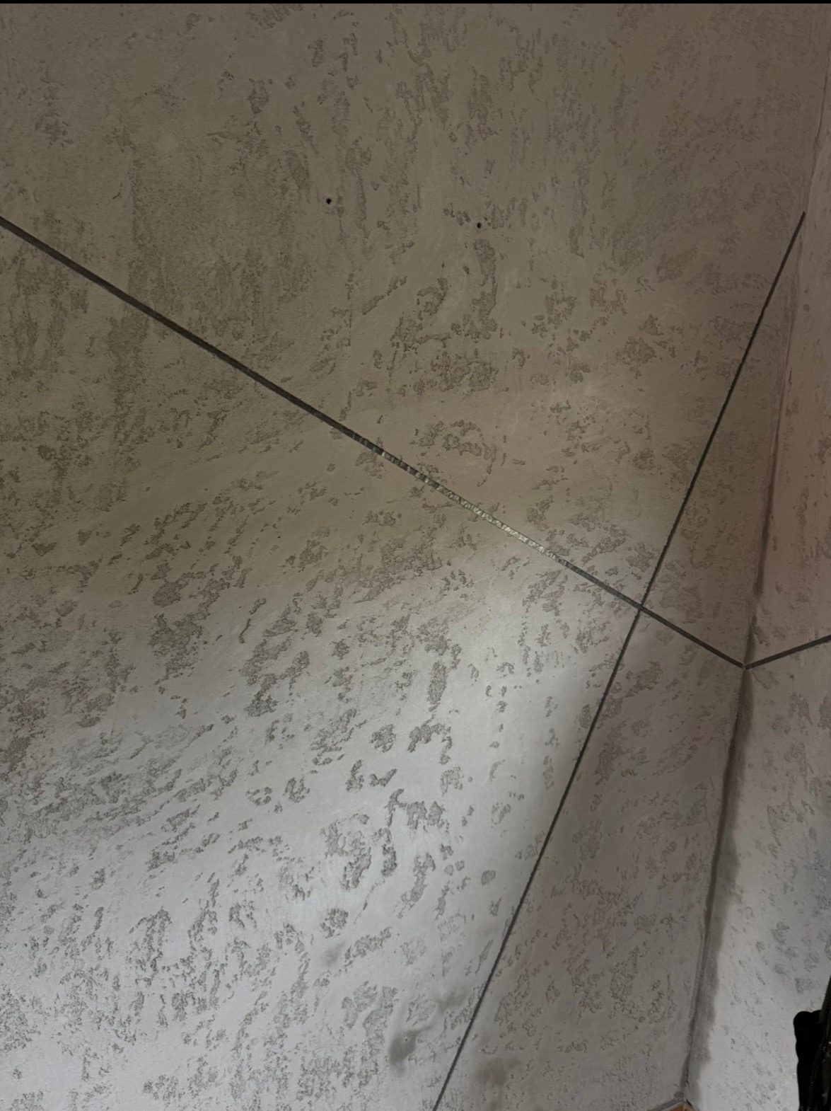 Dekoracyjna ściana w odcieniach szarości z wyraźną fakturą i geometrycznymi listwami, tworzącymi nowoczesny wzór. Minimalistyczny design wnętrza.